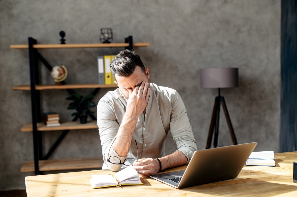 A person working on a computer who is tired