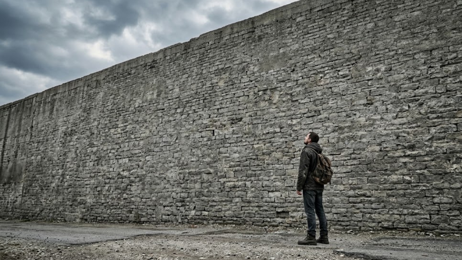 An individual standing in front of a giant wall symbolizing psychological barriers and the roots of unhealthy perfectionism.